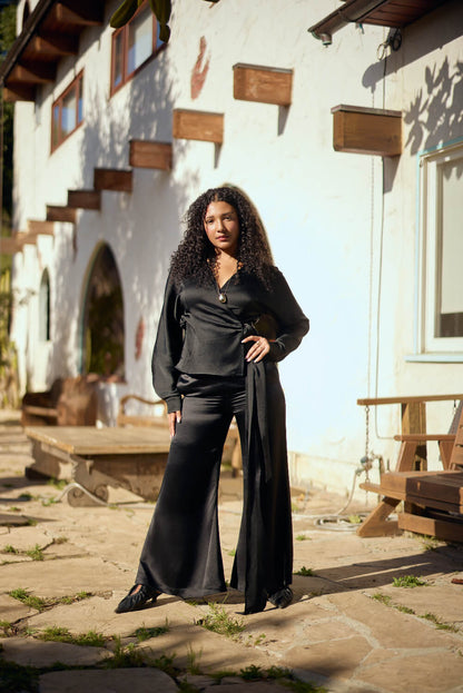 Woman in Siena Long-Sleeve Wrap Blouse  standing outdoors near a white building with wooden accents.